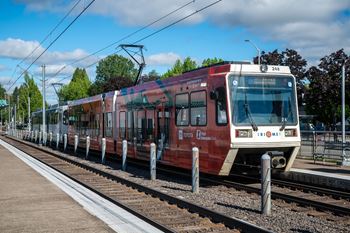 A red and white train is on the tracks with the number 24b on the front.